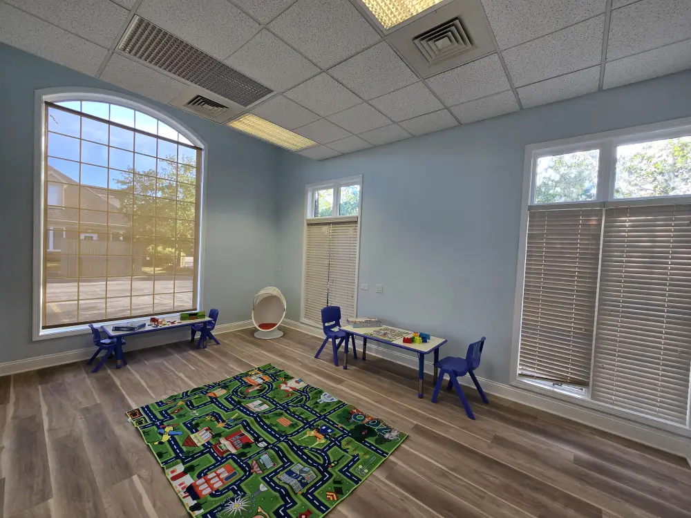 Bright therapy room with child-sized tables and a play mat at Blooming Hearts ABA Therapy Center in Naperville